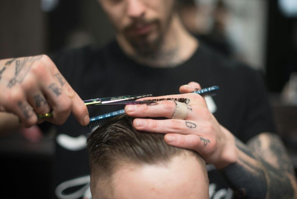 Barber trimming a man’s hair with scissors during a haircut
