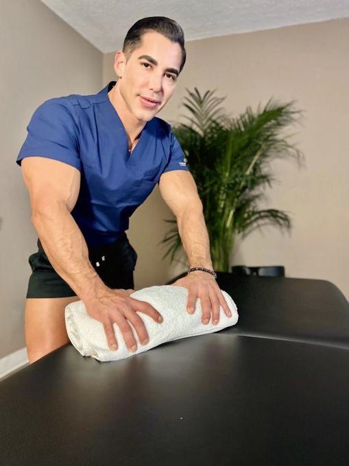 Male massage therapist preparing a treatment table for a professional massage session focused on men’s wellness