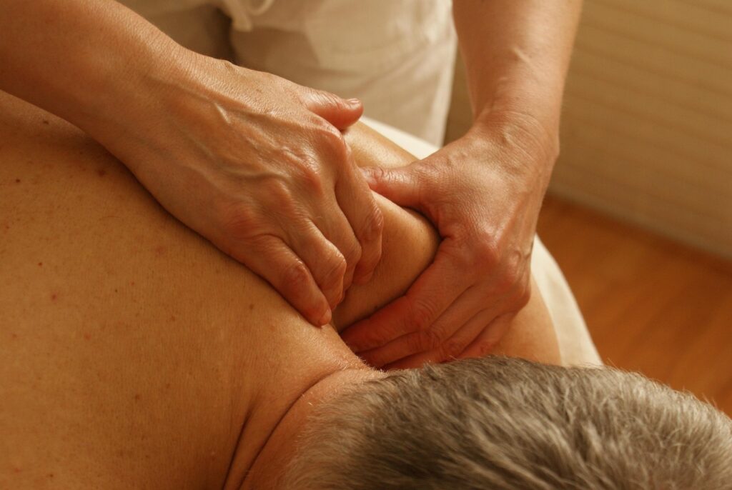 Massage therapist applying pressure to a man’s upper back