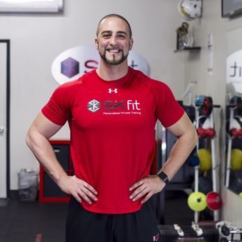 Male personal trainer standing confidently in a gym environment representing strength, professionalism, and trust