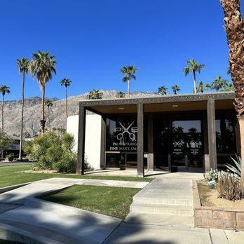 Exterior view of a modern men’s barbershop surrounded by palm trees and desert landscape