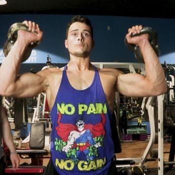 Personal trainer performing upper-body strength training with kettlebells in a gym